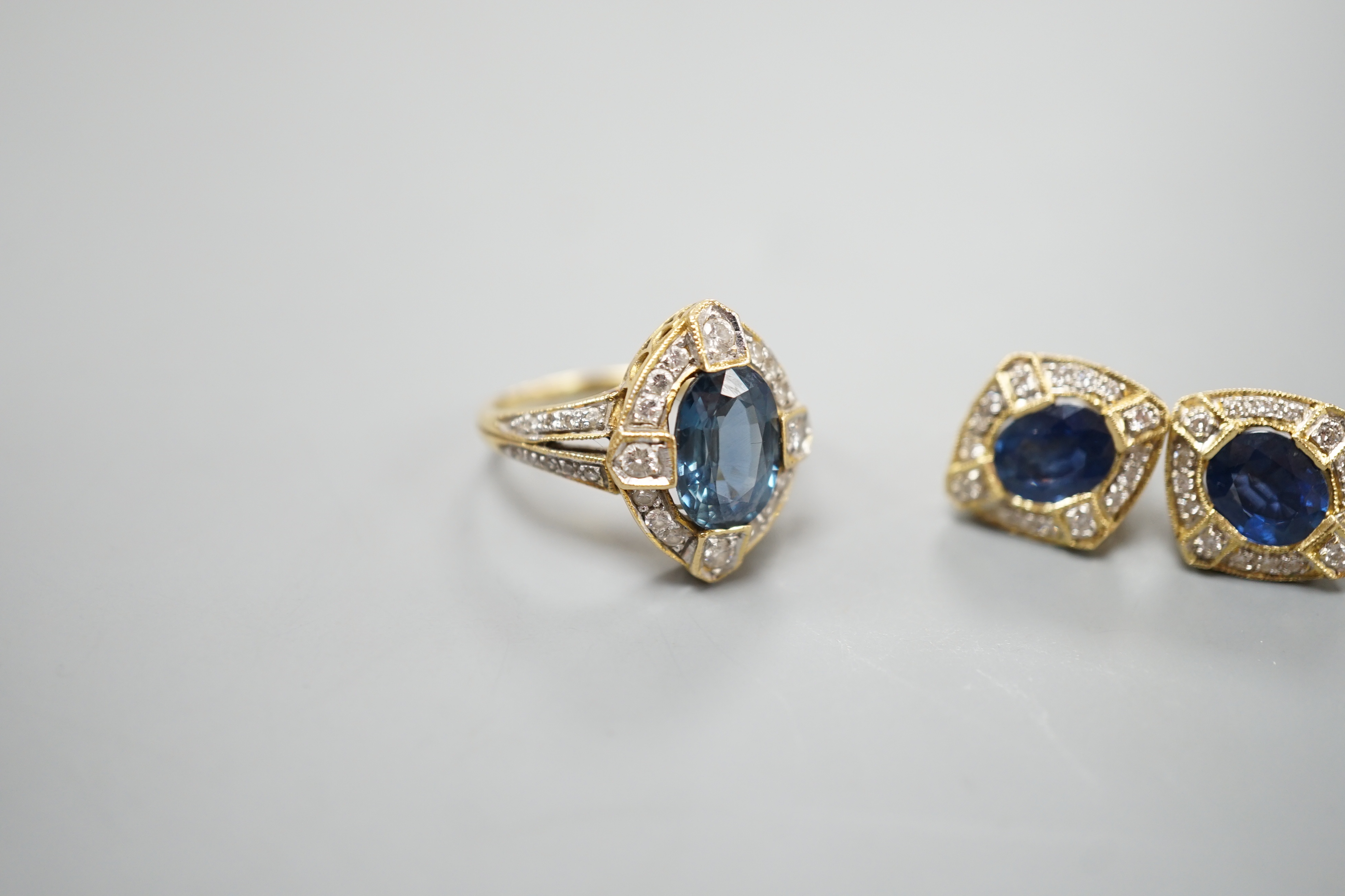 A modern suite of 18k, sapphire and diamond cluster set jewellery, comprising a dress ring, size L/M and pair of earrings, 14mm, gross weight 9.9 grams.